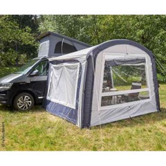 Förtält med fönster fäst vid VW-camper på gräs, säkrat med rep för stabilitet.